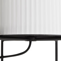 "White ribbed glass lamp shade with black metal base, featuring sleek lines and modern design."