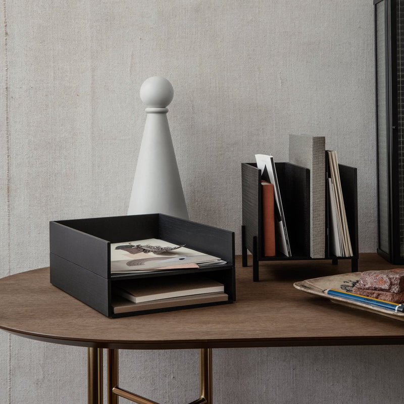 Black storage boxes atop a wooden table with a white decorative piece and minimalist magazine holders.