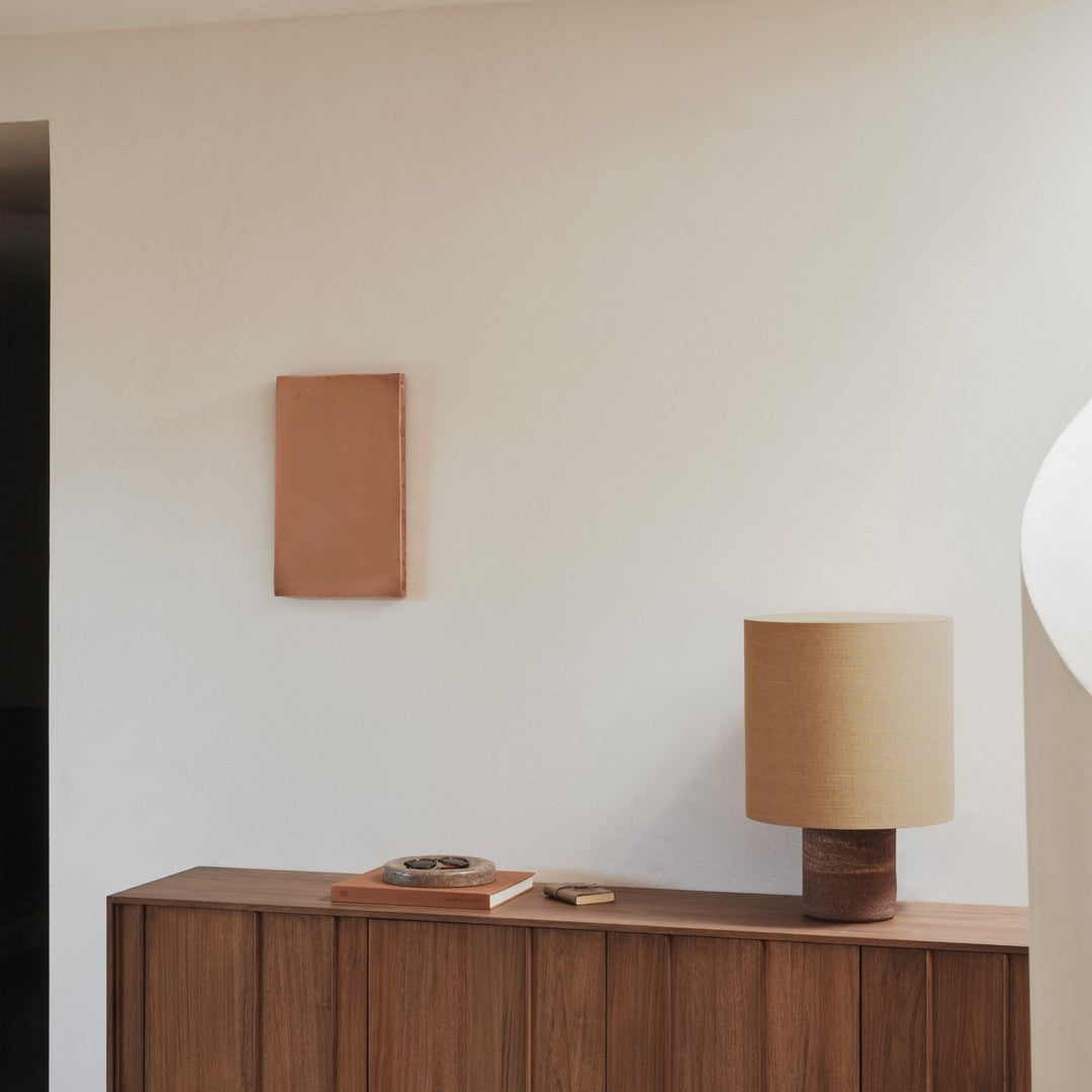 Rustic wood tones with earthy terracotta accents and a soft beige lamp create a warm, modern aesthetic.