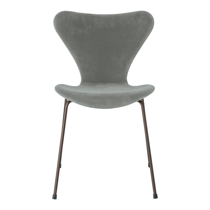 Gray velvet chair with a sleek, modern design and brown metal legs, featuring a smooth, curved silhouette.