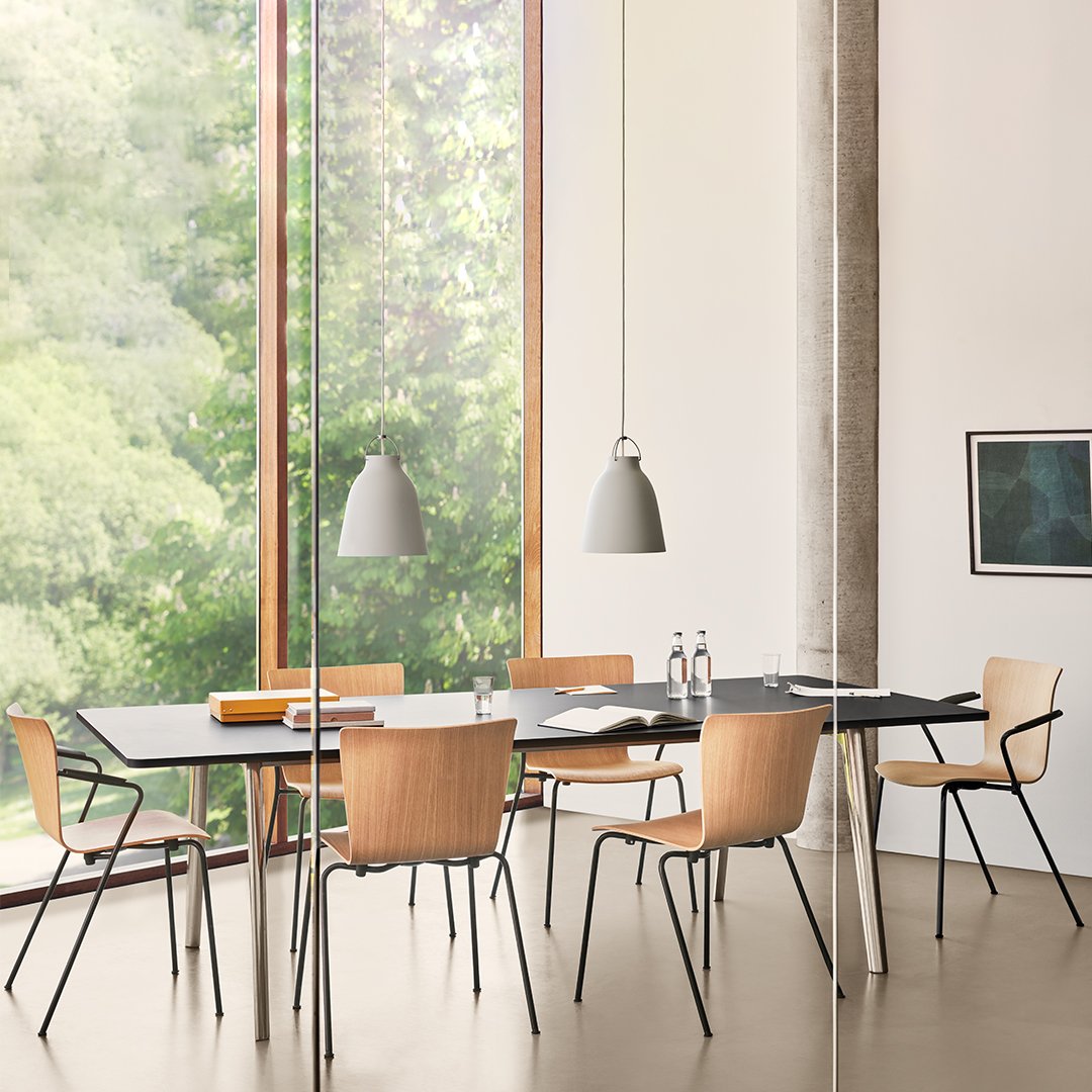 Modern dining room with natural wood tones, black table, beige accents, and minimalist grey pendant lights.