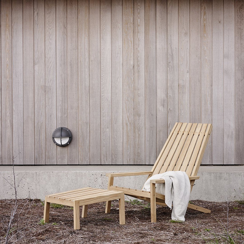 Natural wooden lounge chair and side table with a light grain pattern against a simple, neutral backdrop.