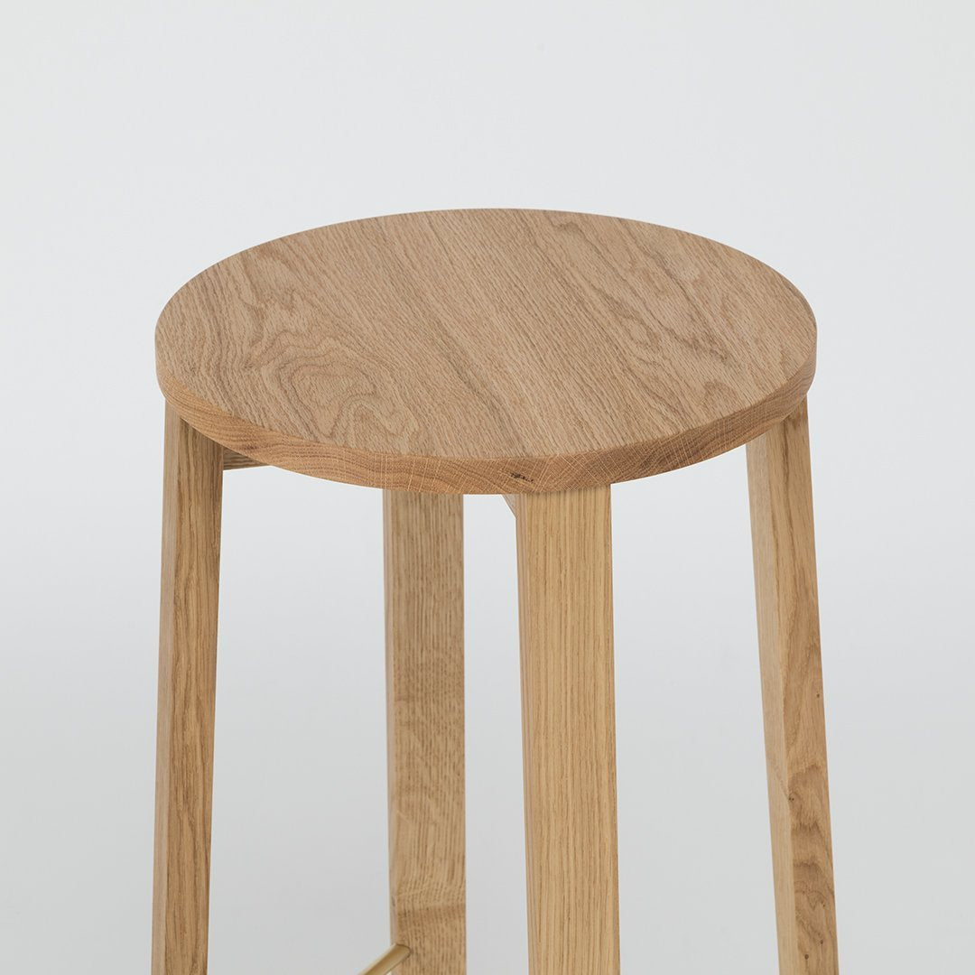Natural wood round stool with a light oak finish and smooth grain pattern, featuring simple, minimalist design.