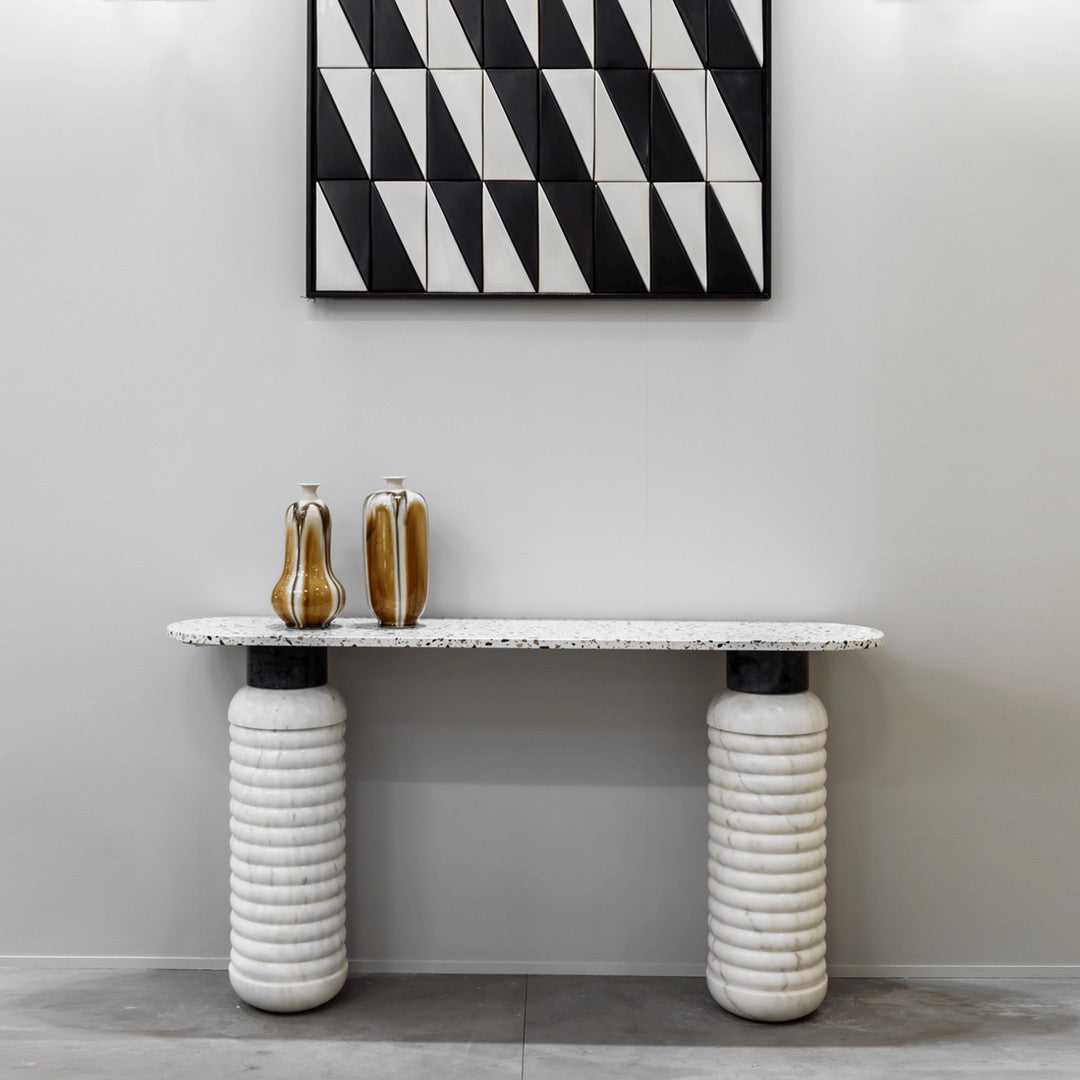 White striped console table with black accents and geometric patterned wall art in monochrome colors.