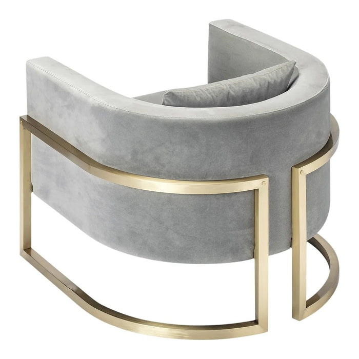 Curved gray velvet chair with gold metal accents, featuring a smooth and modern design. Ideal for stylish decor.