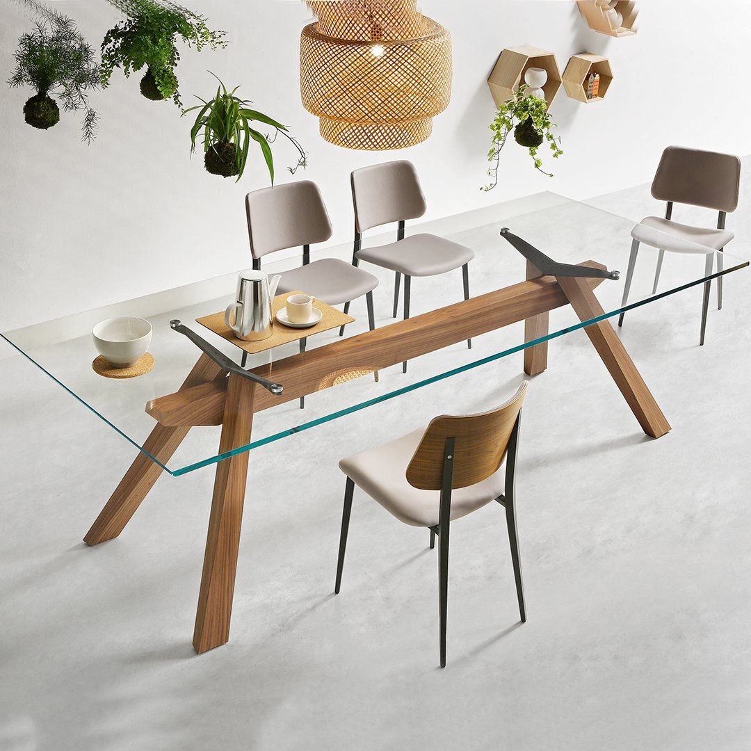 Sleek glass dining table with a natural wood base, complemented by soft beige and gray chairs, creating a modern aesthetic.