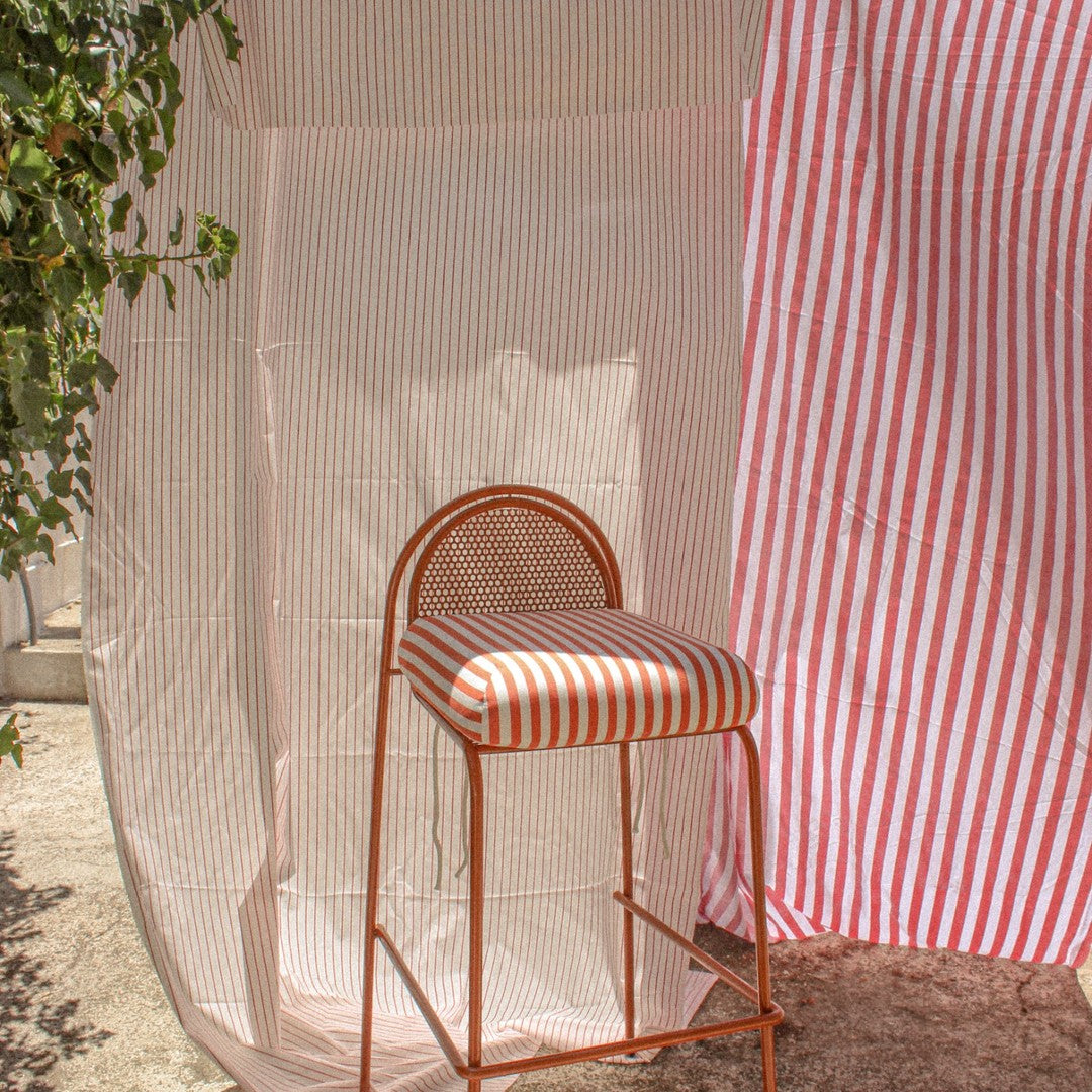 Red and white striped pattern on a bar stool with a matching backdrop, featuring a fresh, vibrant design.