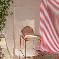 Red and white striped pattern on a bar stool with a matching backdrop, featuring a fresh, vibrant design.