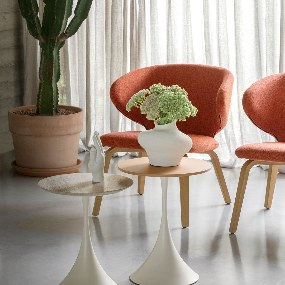 Orange upholstered chairs, white vases, and modern tables against a neutral backdrop with green plant accents.