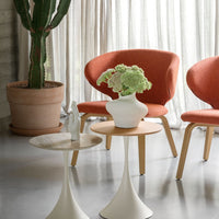 Orange upholstered chairs, white vases, and modern tables against a neutral backdrop with green plant accents.