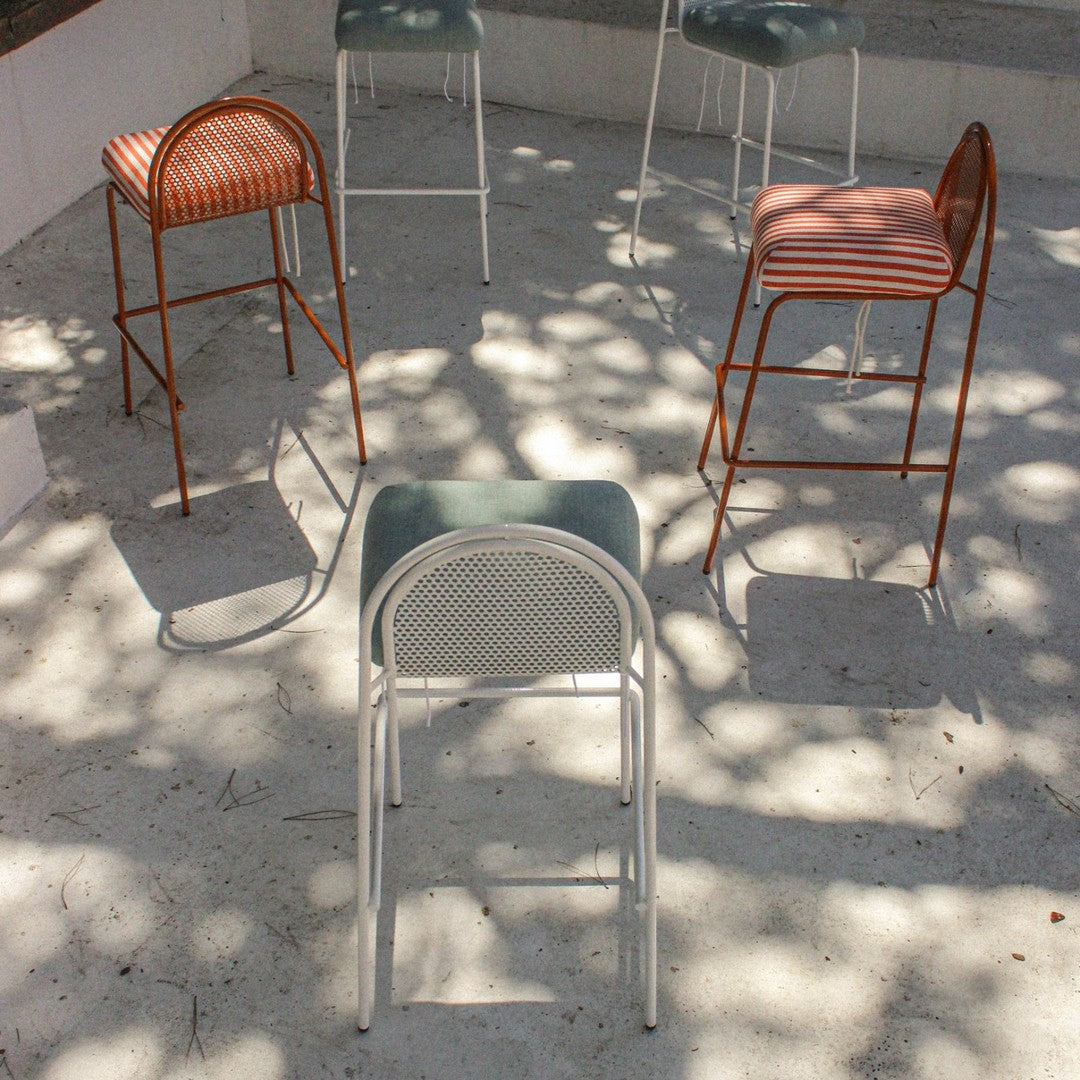 Colorful bar stools featuring green, orange, and striped patterns arranged in a modern outdoor setting.