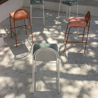 Colorful bar stools featuring green, orange, and striped patterns arranged in a modern outdoor setting.