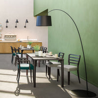 Modern dining room featuring green walls, black lamp, and a mix of white and dark wood furniture with subtle patterns.