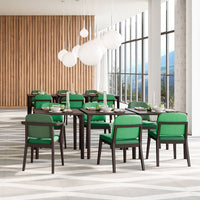 Green and black dining chairs arranged around a dark wood table in a modern, light-filled space.