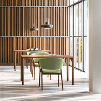 Wooden dining room with light green chairs and black pendant lights, showcasing a modern, natural aesthetic.