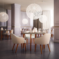 Modern dining room featuring soft beige chairs, light wooden legs, and elegant white pendant lights against a muted backdrop.