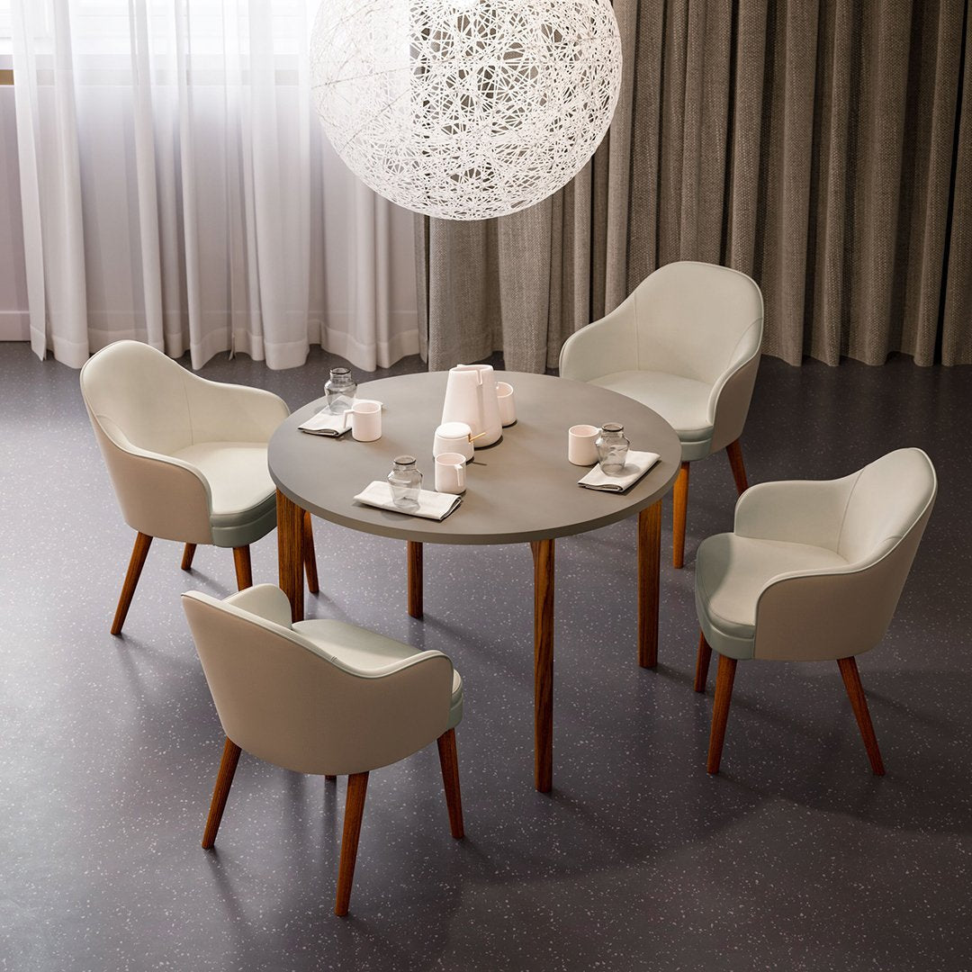 Light gray round table with four matching cream chairs featuring wooden legs, set against a neutral backdrop.