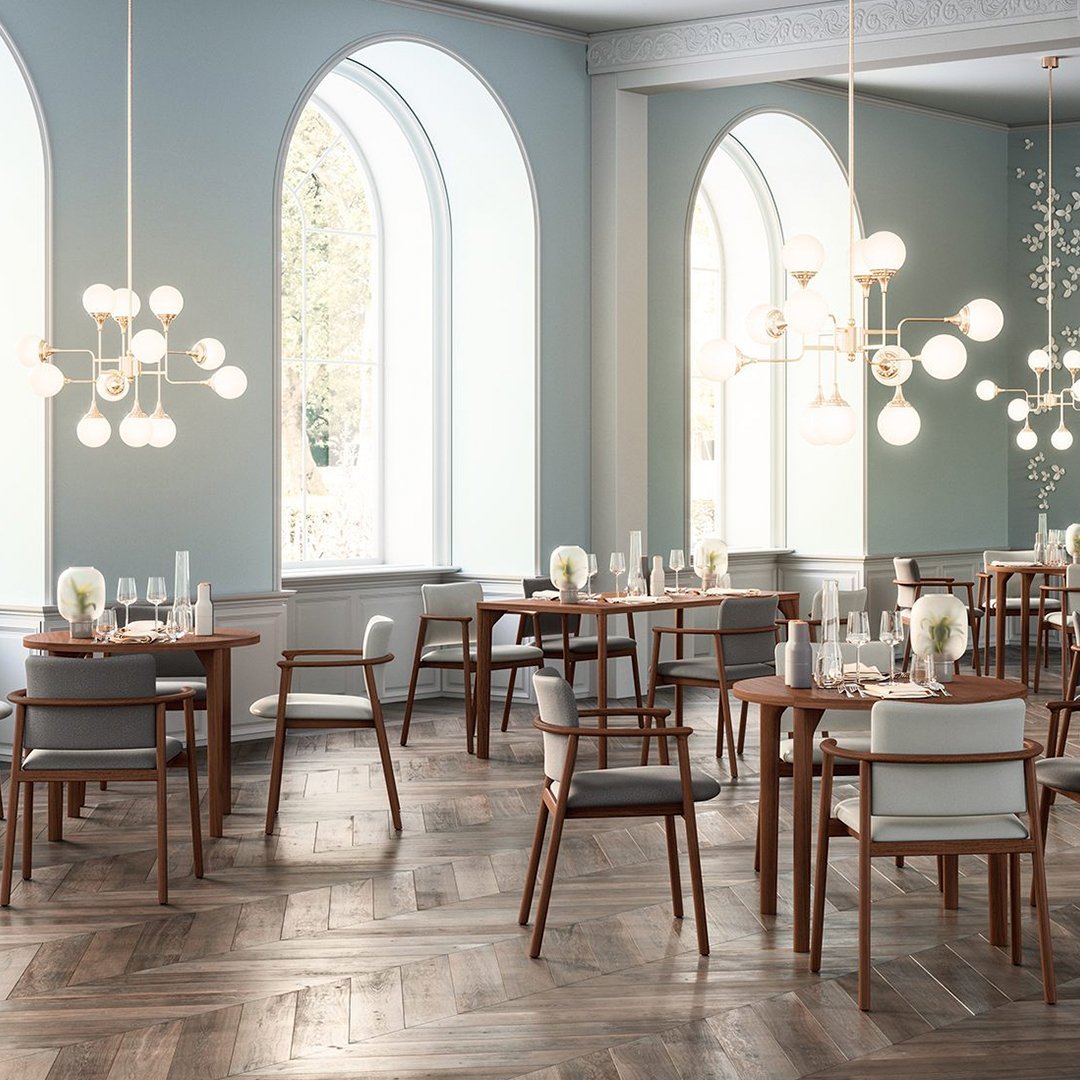 Elegant dining room featuring light blue walls, rich wood floors, and stylish light fixtures with white and gold accents.