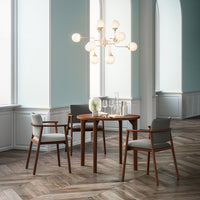 Modern wooden dining table with gray upholstered chairs, featuring light wood flooring and soft blue walls.