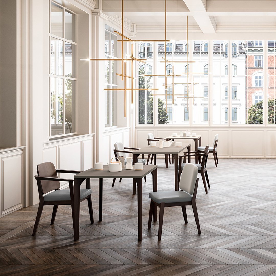 Modern dining space featuring warm wood tones and light gray cushions against a herringbone patterned floor.