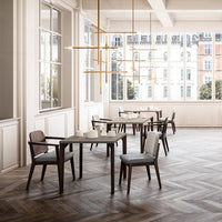 Modern dining space with herringbone wood flooring, neutral furniture, and warm gold accents in natural light.