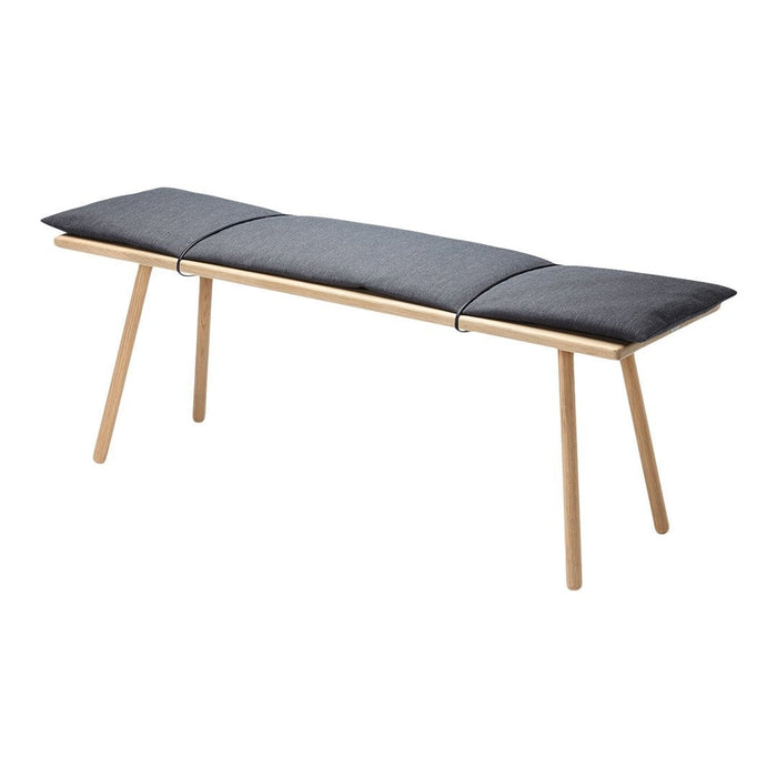 Gray padded bench with a minimalist design, featuring light wooden legs and simple, sleek lines.
