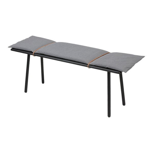 Gray padded bench with black metal legs and brown accent strap detail. Minimalist design with modern touch.