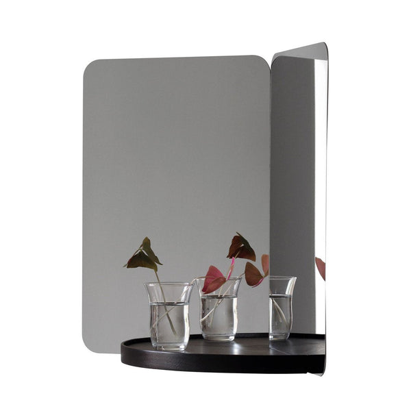 "Modern two-tone mirror with sleek black base, reflecting subtle patterns and natural greenery."