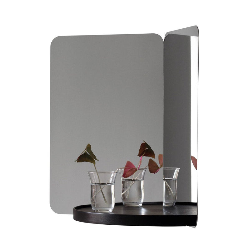 "Modern two-tone mirror with sleek black base, reflecting subtle patterns and natural greenery."