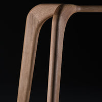 Natural wood grain with light brown tones and smooth curves, featuring minimalist design against a black background.