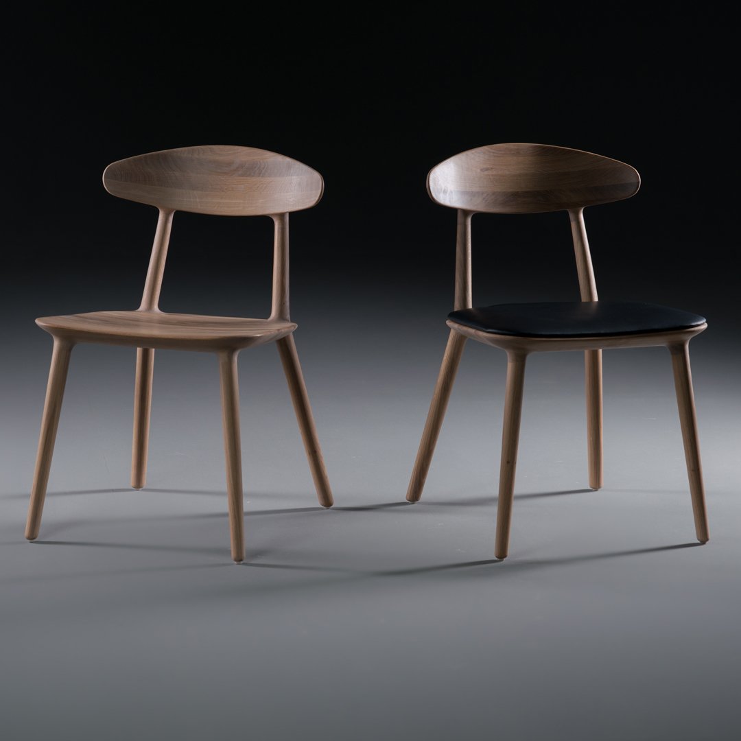 Two modern wooden chairs: one with a light wood finish and the other featuring a dark seat. Simple, elegant design.