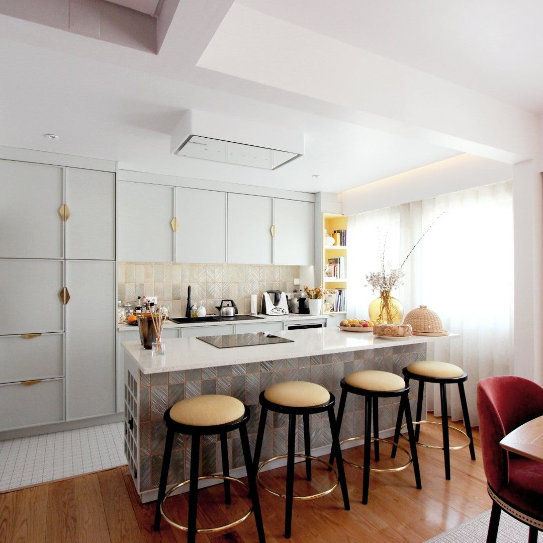 Modern kitchen featuring soft gray cabinets, warm wood floors, golden accents, and subtle white and beige patterns.