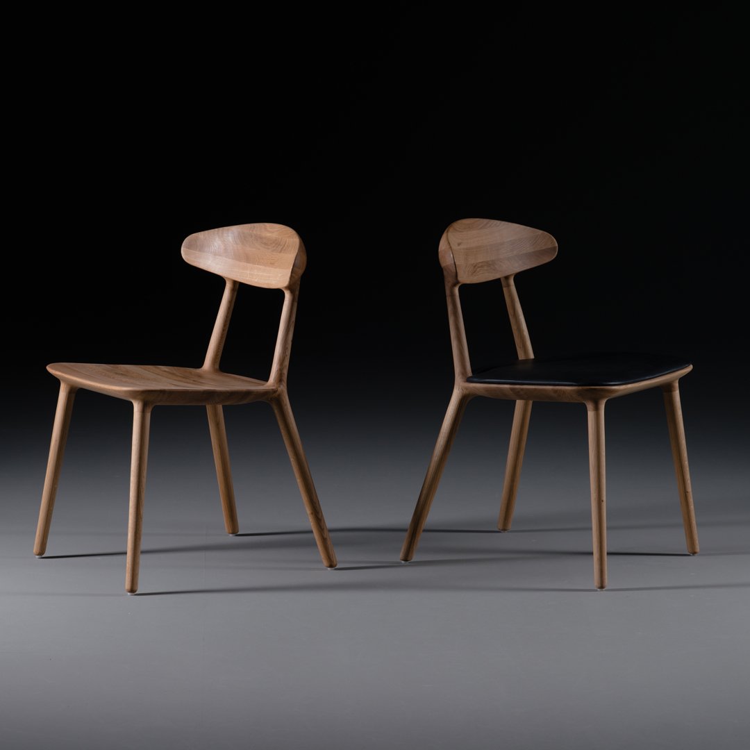 Two wooden chairs in light and dark finishes, featuring smooth surfaces and modern, minimalist designs.
