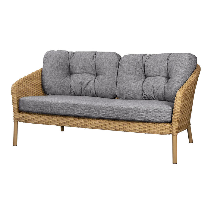 Gray tufted cushions on a natural wicker sofa, featuring a blend of textures and neutral tones for modern decor.
