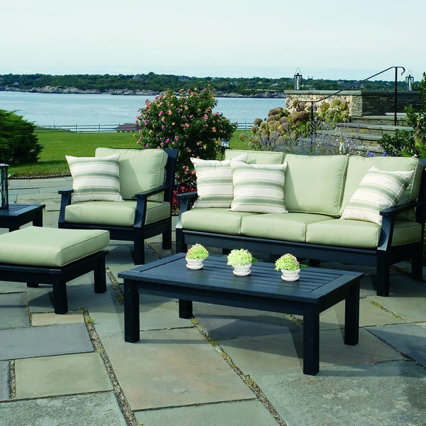 Light green cushions with striped accents on black furniture, set against a scenic outdoor backdrop.