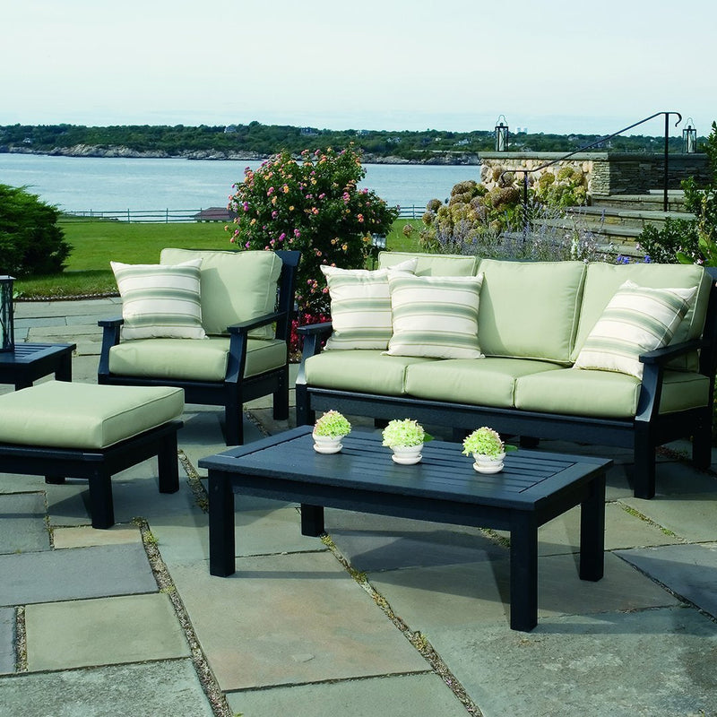 Light green cushions with striped accents on black furniture, set against a scenic outdoor backdrop.