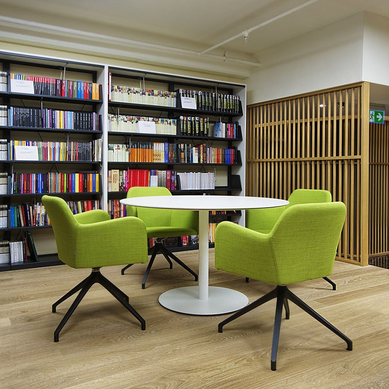 "Vibrant green armchairs with sleek black bases, paired with a minimalist white round table, set against wooden flooring."
