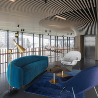 Teal velvet sofa, white modern chair, navy accent chair, gold lamp, and geometric patterns create a stylish living space.