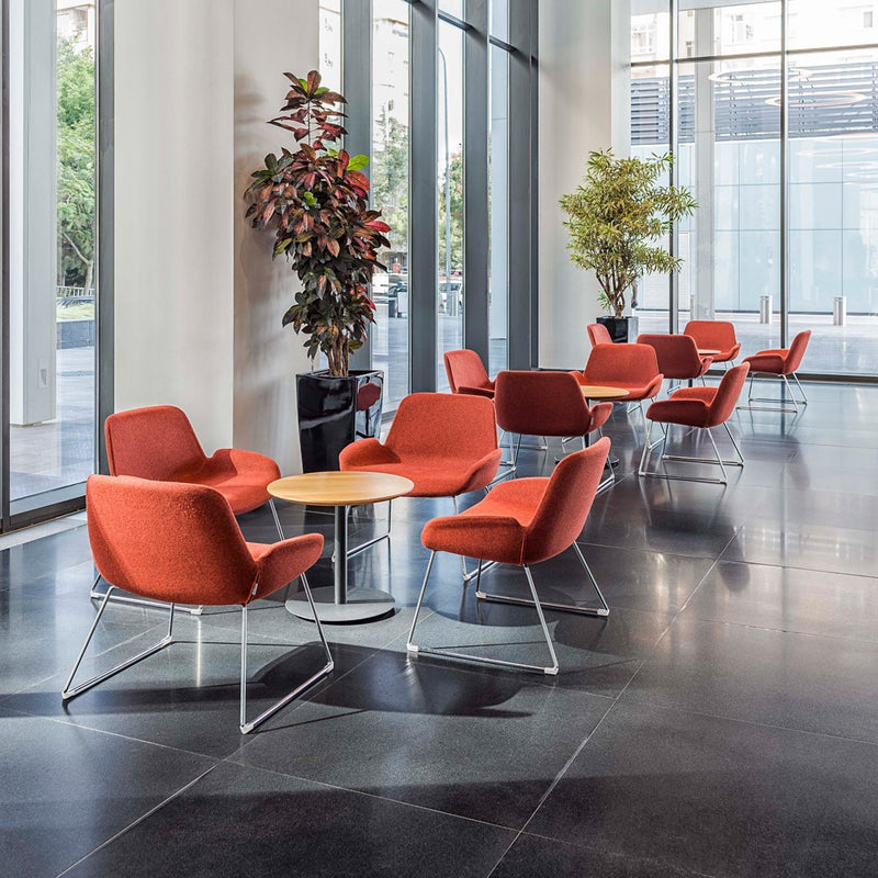 Orange upholstered chairs around a round wooden table, set in a modern, bright, and open space.