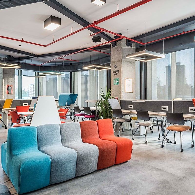 Modern couch in shades of teal, gray, and orange, featuring a contemporary design within a stylish office setting.