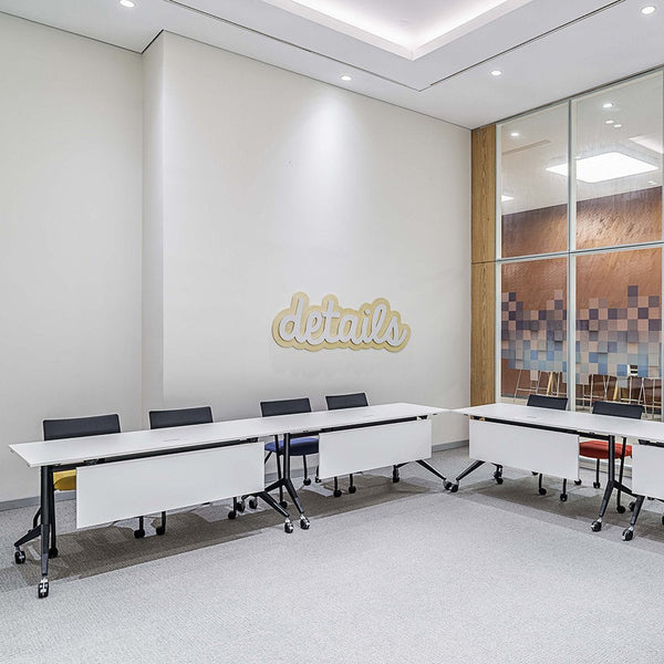 Modern office interior featuring white tables with black, yellow, blue, and orange accents on seating and walls.