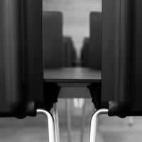 Black chairs with sleek metal legs, featuring a minimalist design against a blurred background.