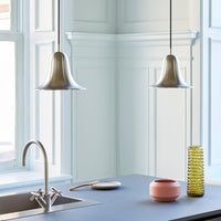 "Silver pendant lamps with soft curves above a blue countertop; pink and green decorative vases add vibrant color."