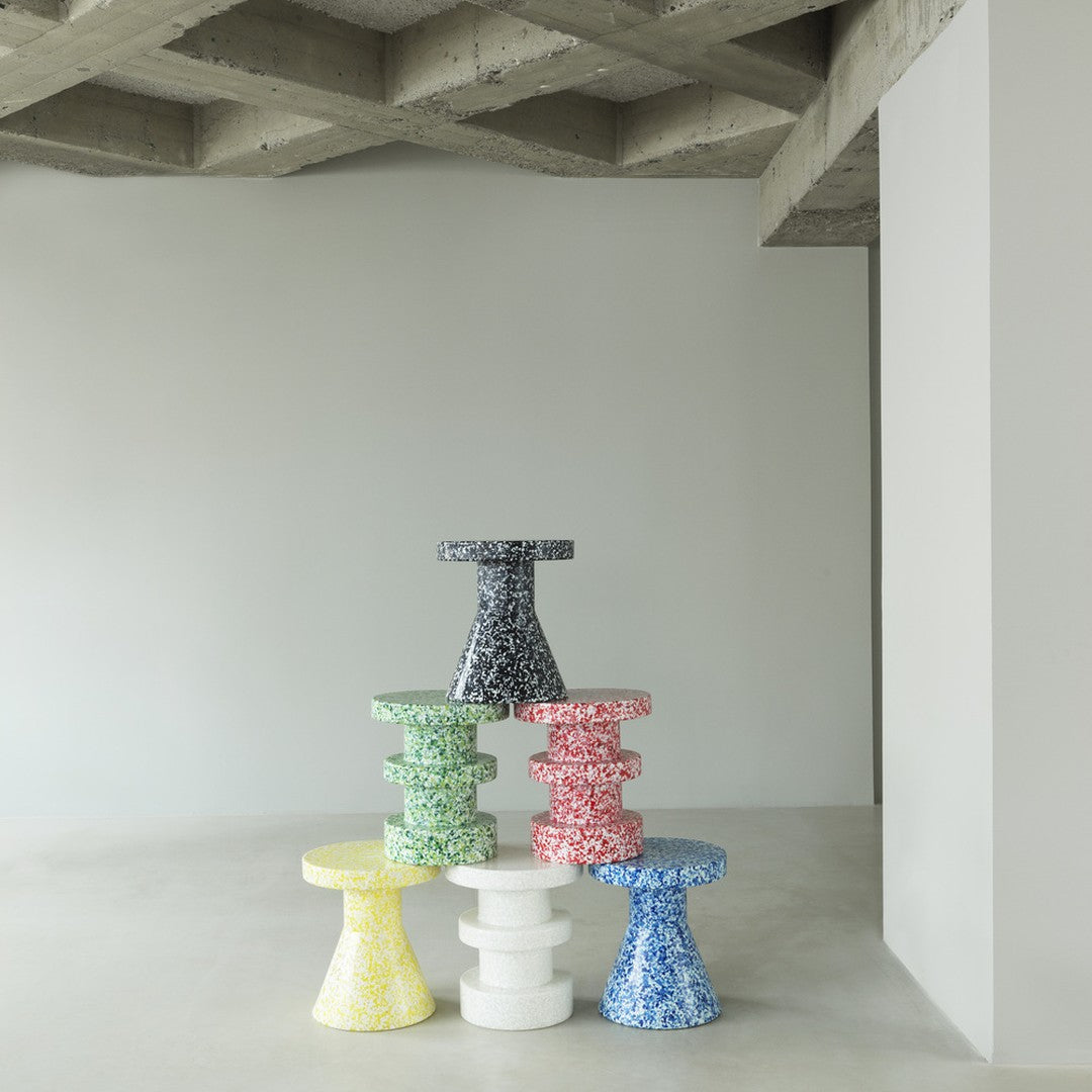 Colorful patterned stools stacked in yellow, green, red, blue, white, and black against a minimalist background.