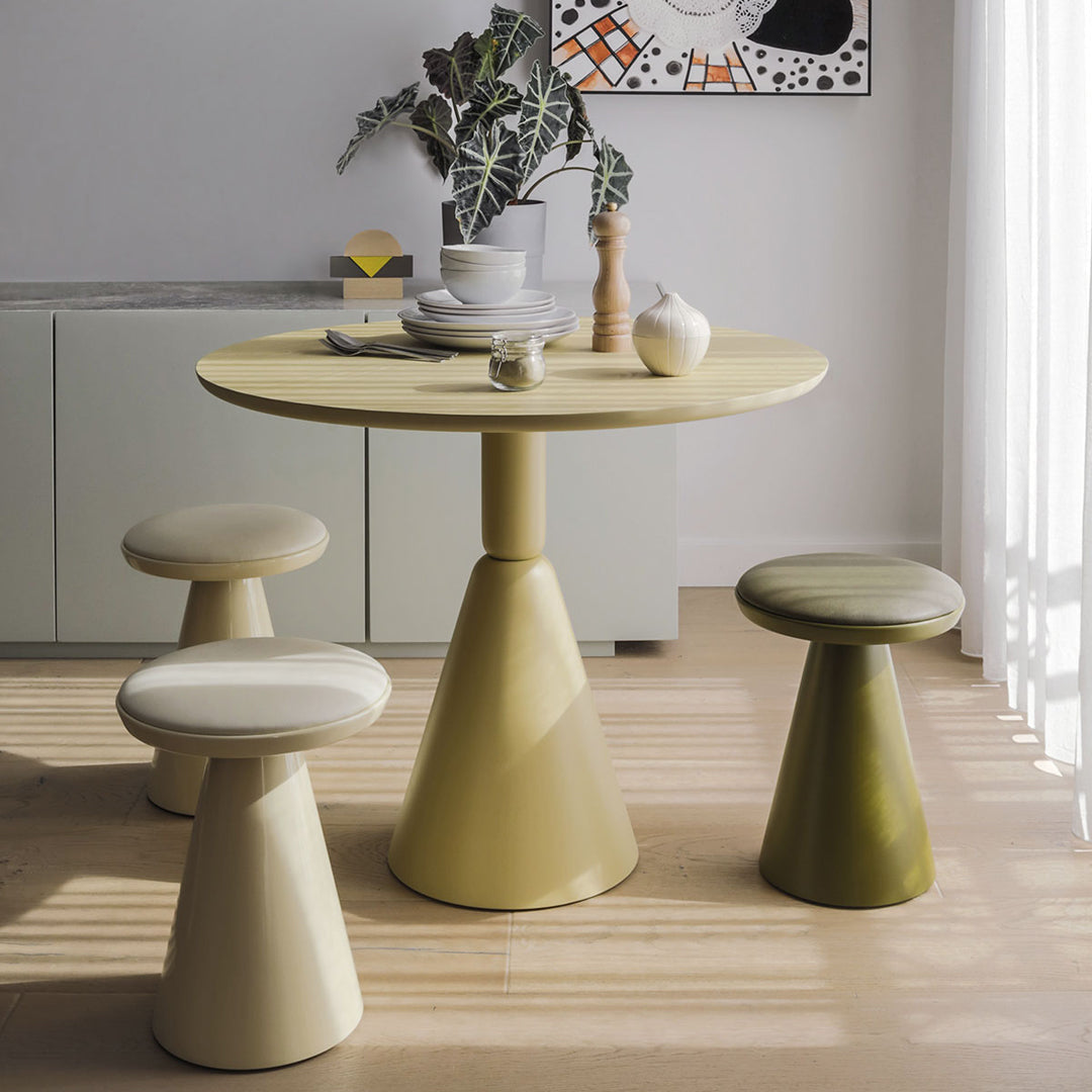 Modern round table and cone-shaped stools in soft yellow, muted green, and cream colors, featuring minimalist design.