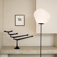 "Modern black candle holder with minimalistic design against a neutral wall, complemented by a soft white lamp."