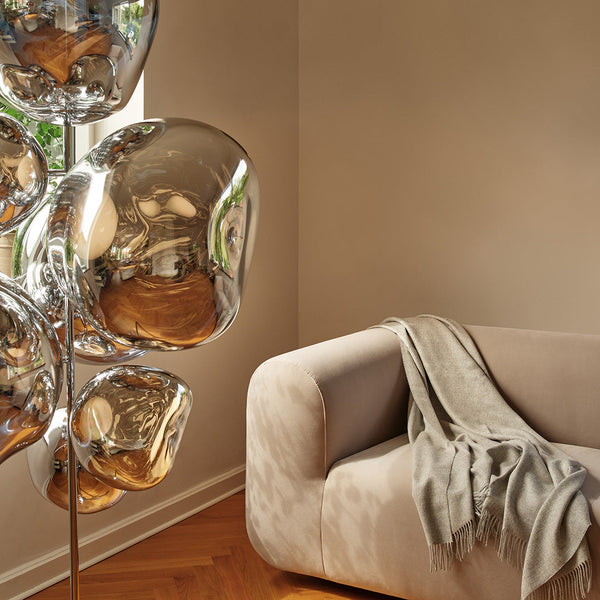 Silver balloon decor against a warm beige wall, complemented by a soft gray throw on a light-colored sofa.