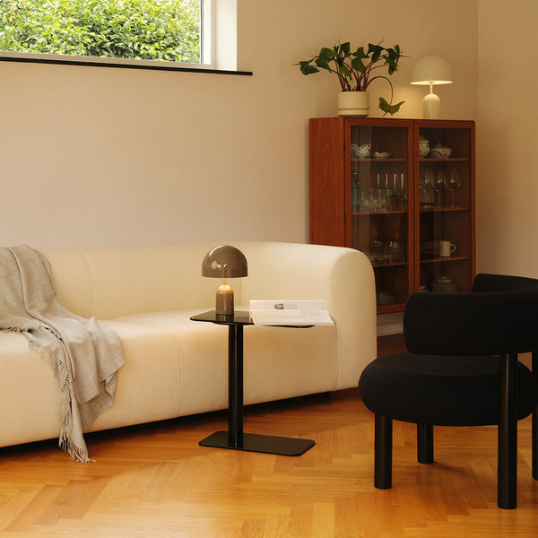 "Modern living room featuring a white curved sofa, black accent chair, and warm wood flooring with subtle grain patterns."