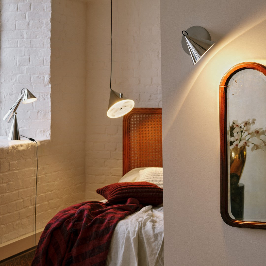 Modern bedroom with warm burgundy throws, sleek chrome accents, and soft beige walls. Sophisticated lighting fixtures enhance decor.