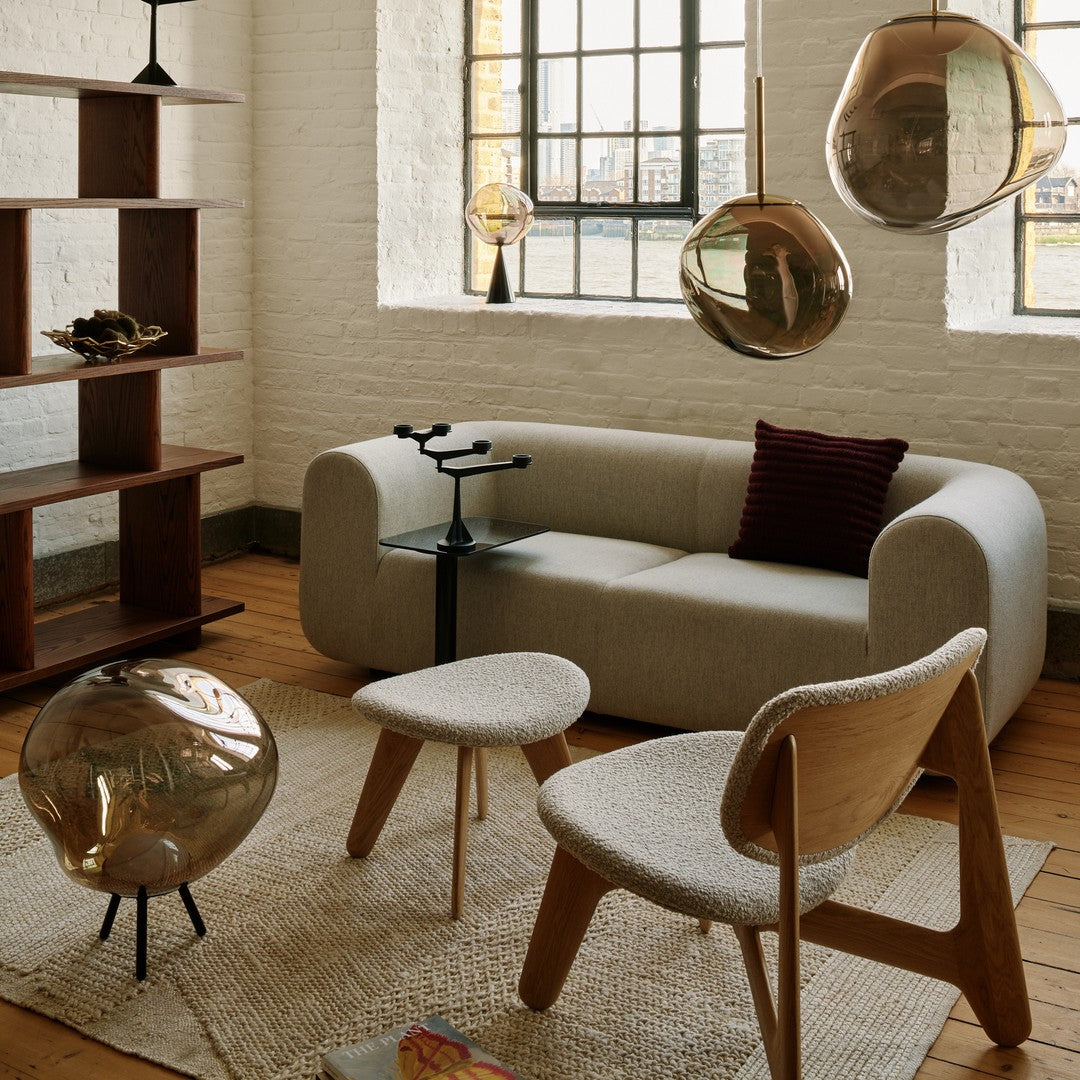 Modern living room with a light gray sofa, wooden accents, gold pendant lights, and neutral-toned decor.
